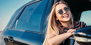 Woman hanging out passenger side window of sedan.