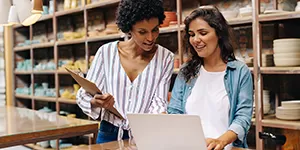 Two coworker women looking at a laptop in a shop.