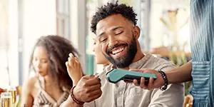 Guy using a tap credit card to pay at a restaurant.